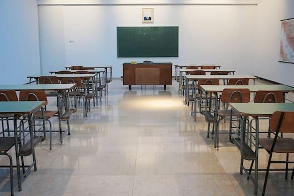 A classroom with desks and a green "blackboard" at the front of the room 