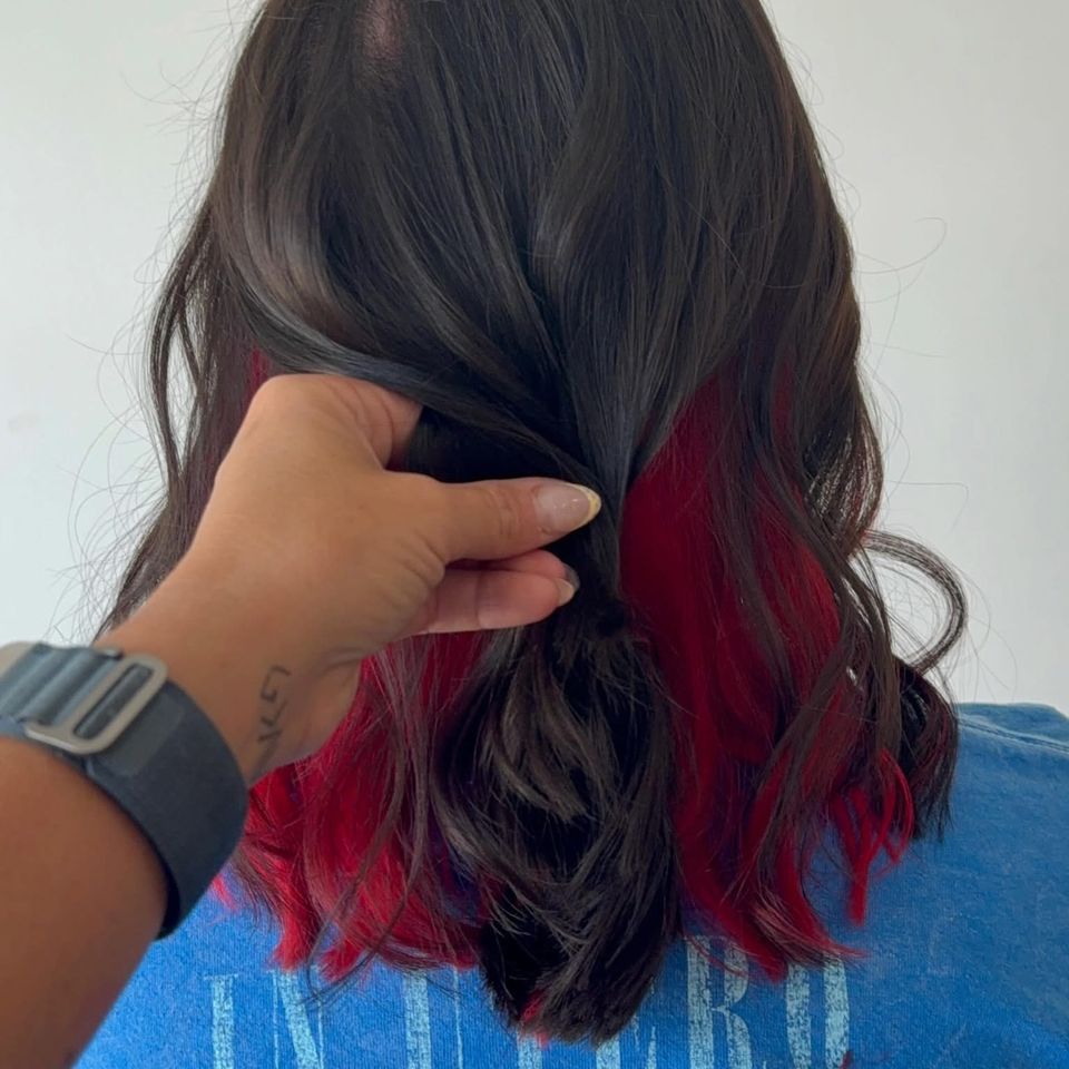 Dark hair with bold red peekaboo underlayer revealed after color service in Columbiana AL