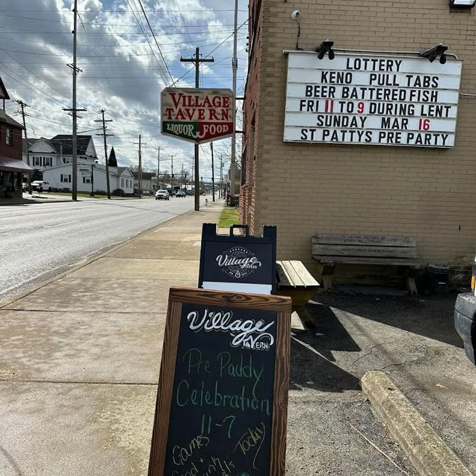 Side view of Village Tavern building with brick exterior, sign, and street view nearby