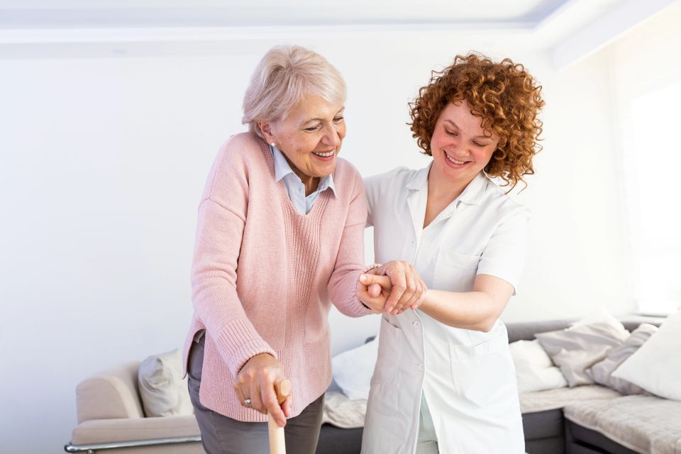 Caregiver helping senior woman with cane walk safely during mobility care on Long Island NY