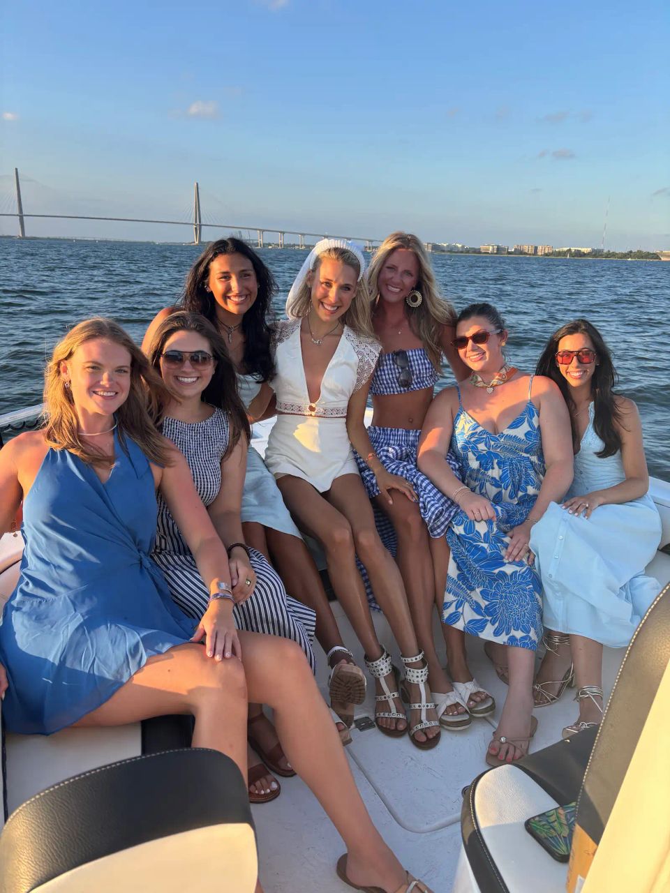 Group of women celebrating a Charleston bachelorette party on a boat at sunset with the Ravenel Bridge in the background