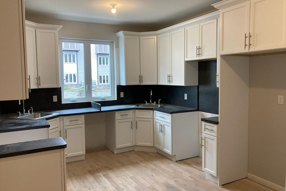 White kitchen with black countertops and custom cabinetry by Ultimate Kitchens.