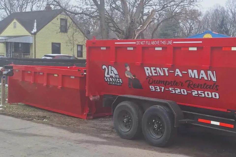 Rent-A-Man Dumpster Rentals truck placing a dumpster at a residential property.