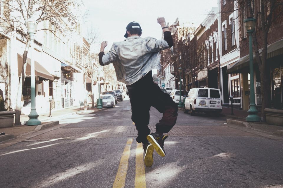 A person clicking their heels together in a dance walking down a city street on the double yellow line. 