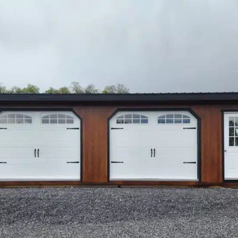 Stained wood double-wide garage with two white carriage doors in East Tennessee