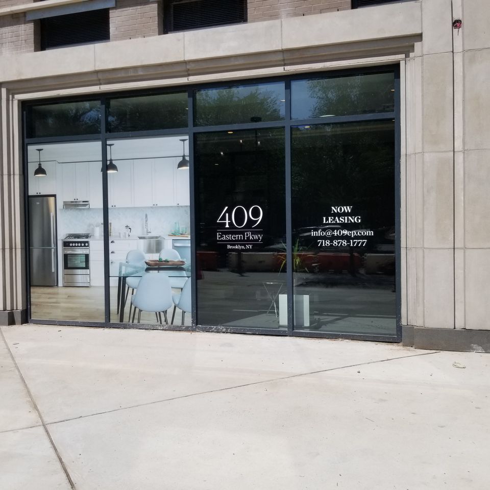 White cut-vinyl address logo and leasing details applied to a large storefront window