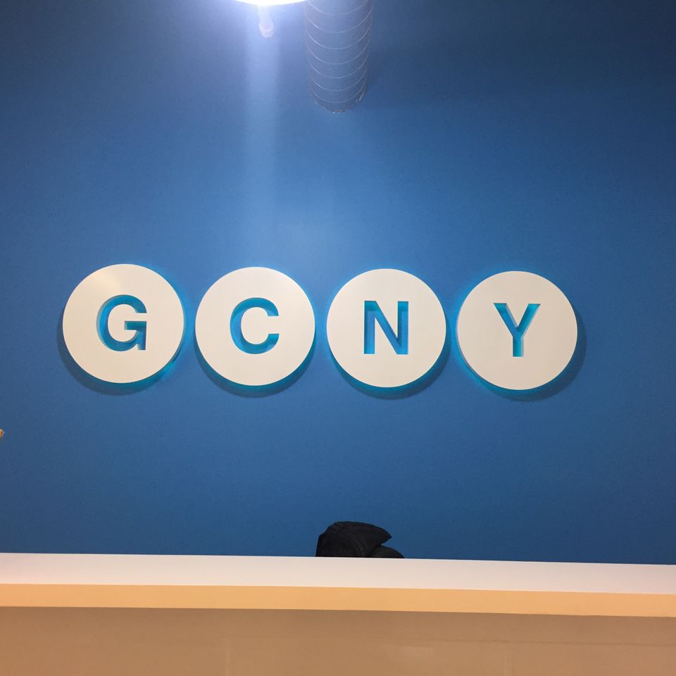 White dimensional letters on round white backers mounted across a blue interior reception wall above a counter