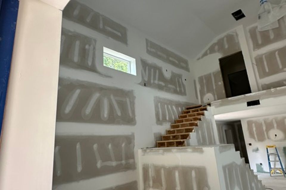 Interior of steel building under construction with drywall and wooden staircase representing steel building interiors in Alabama