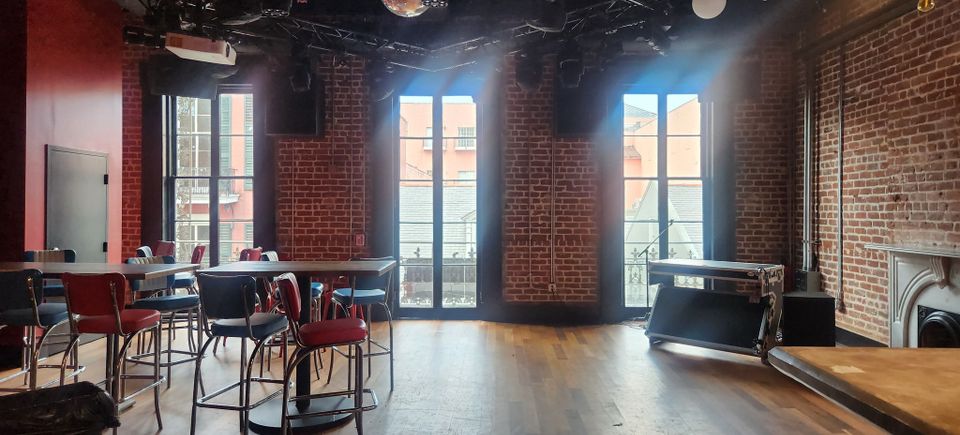 Interior of a Bourbon Street balcony venue with brick walls, and seating prepared for Carpe Diem Events VIP balcony parties