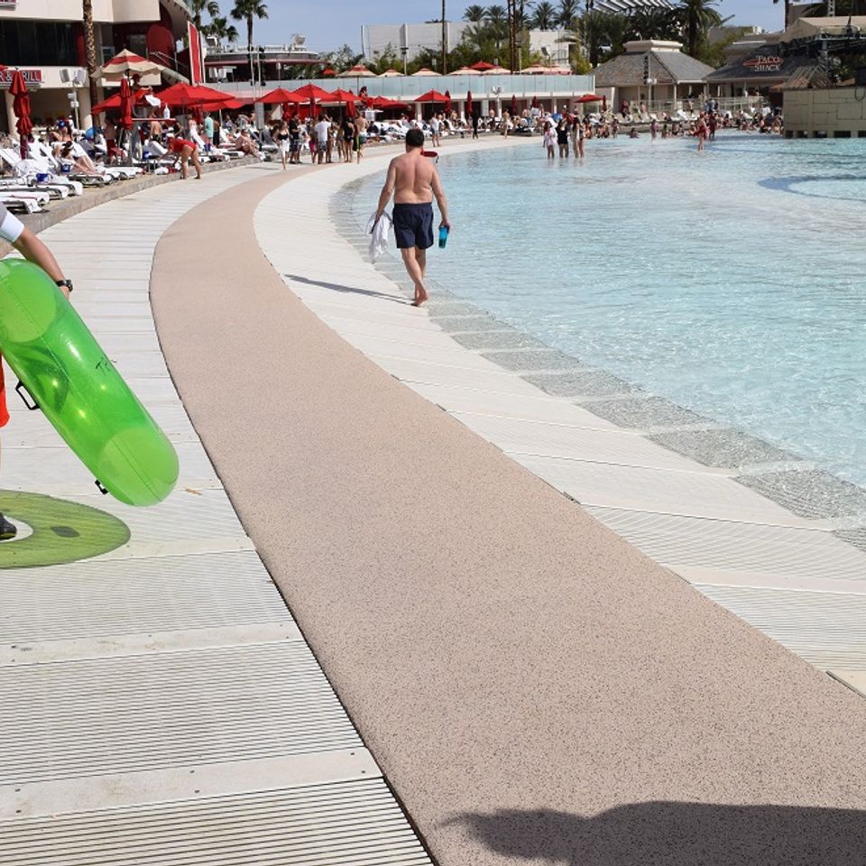 Curved EverStone Flex walkway installed alongside a large commercial swimming pool.