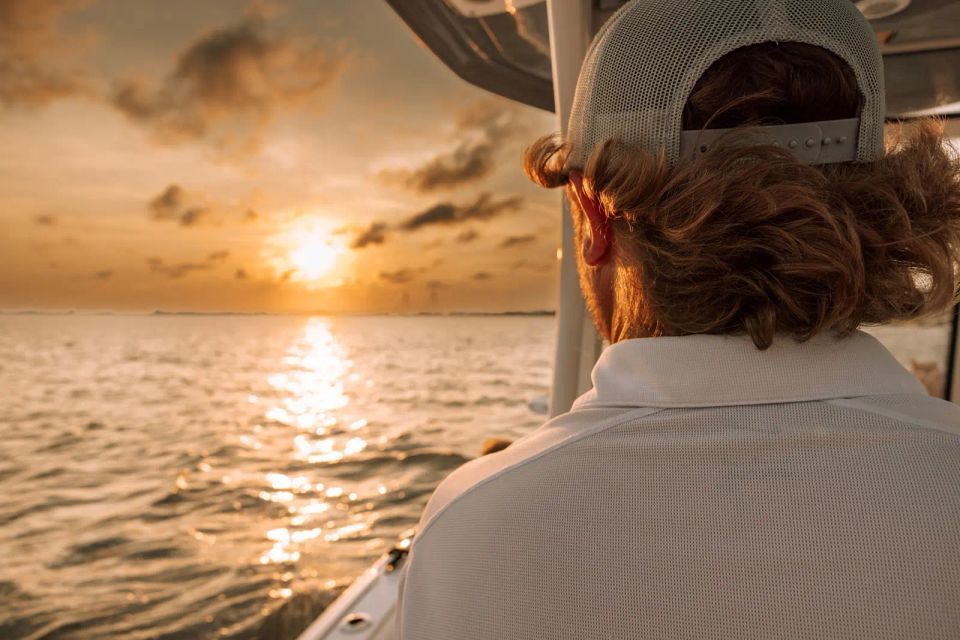 View over the captain’s shoulder during a Charleston sunset cruise, golden sun reflecting on the water.