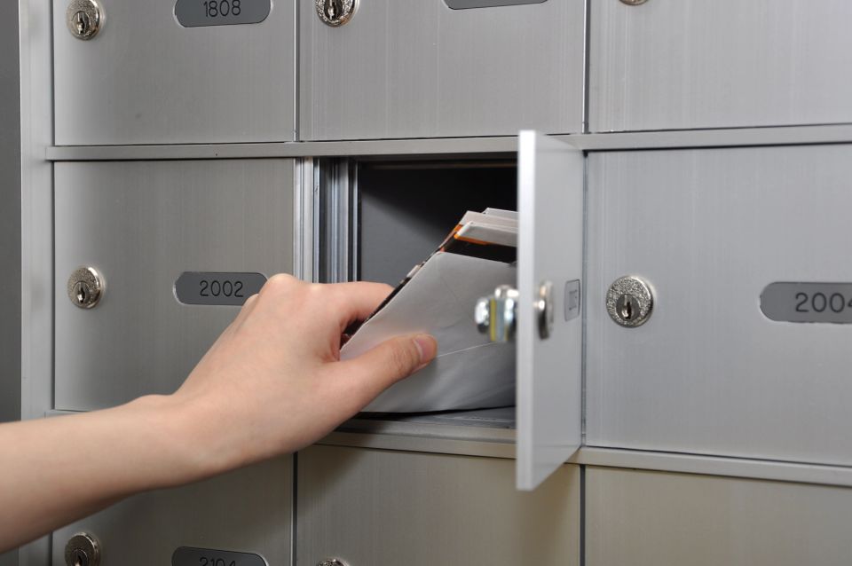 A person taking mail from her mailbox