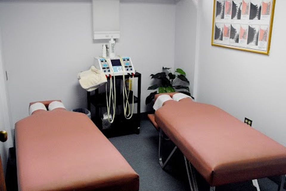 Two chiropractic treatment tables with therapy equipment in a clean, private treatment room at Massaro Chiropractic LLC.