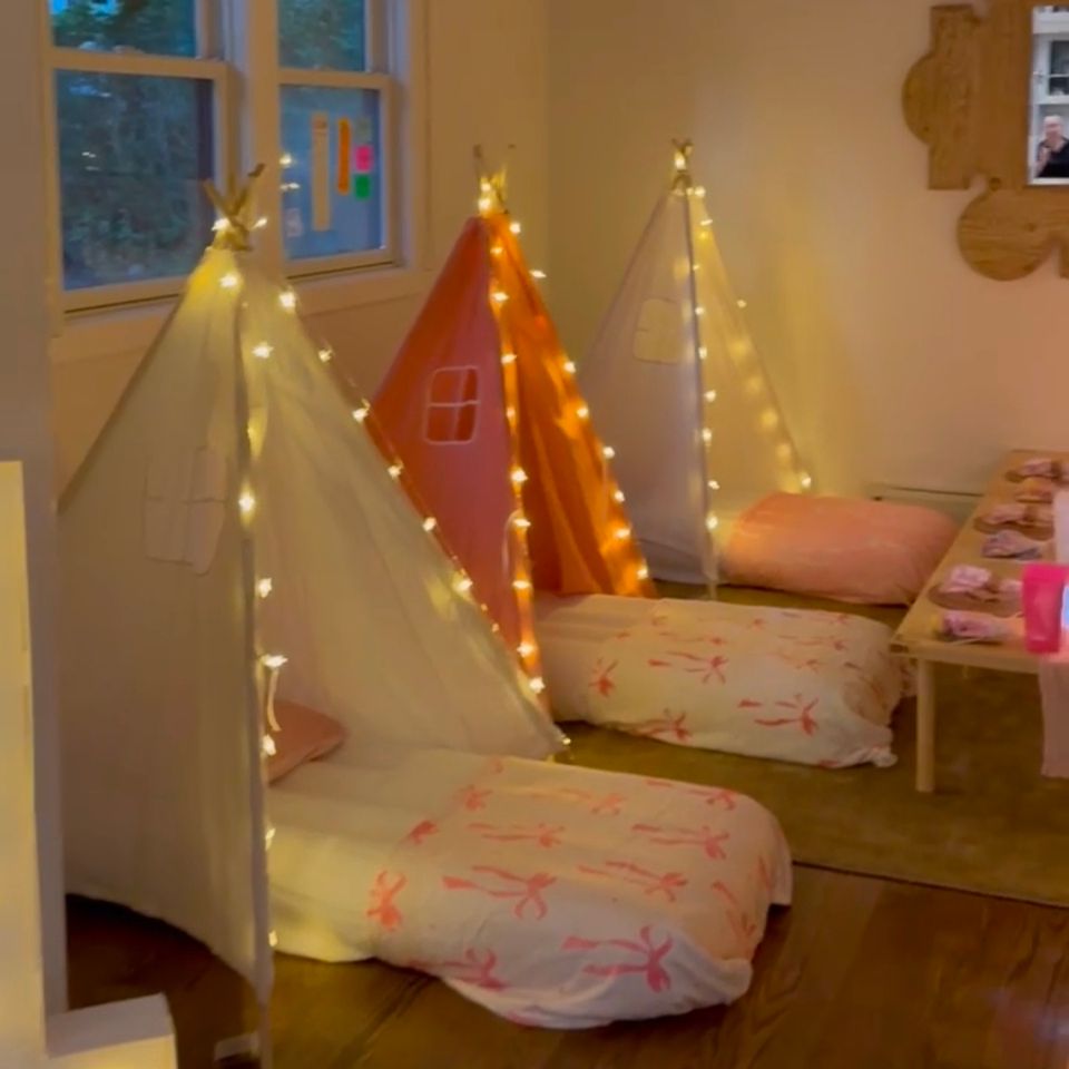 Three lighted teepee tents with bow-print bedding arranged for a sleepover party in the Hamptons NY