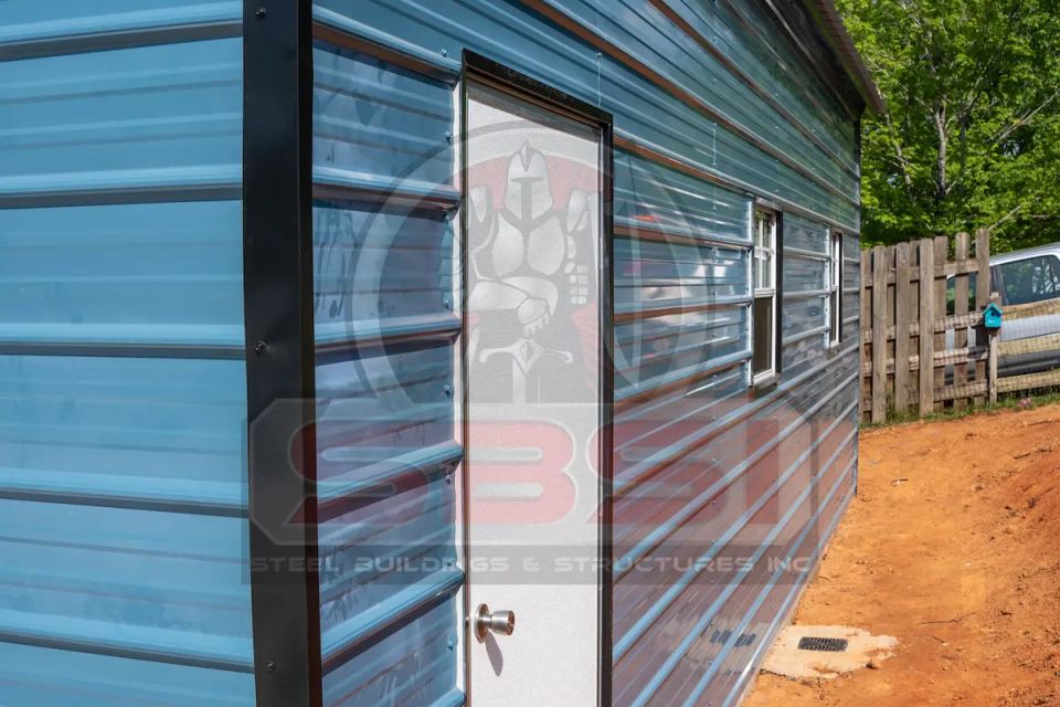 Blue steel building side wall with white entry door and windows with SBSI watermark representing steel buildings in Alabama