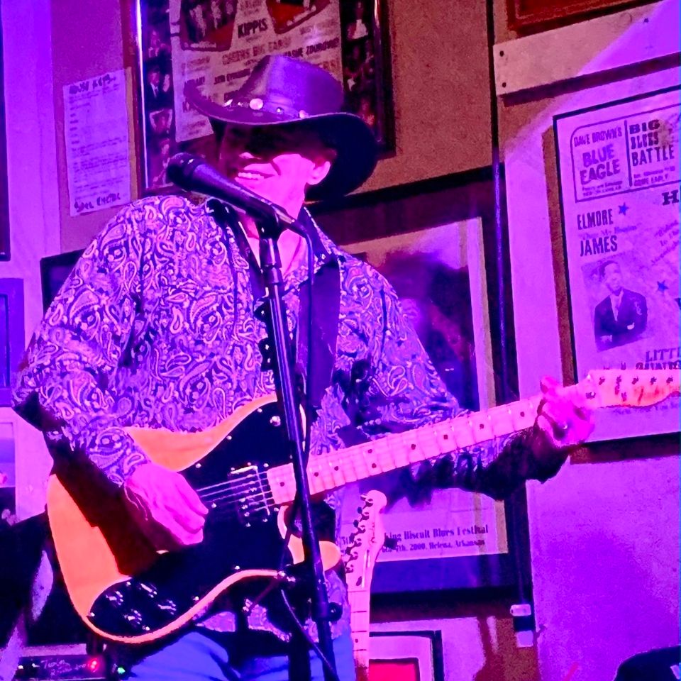 Roadside guitarist in a cowboy hat playing electric guitar during a live blues and Americana set