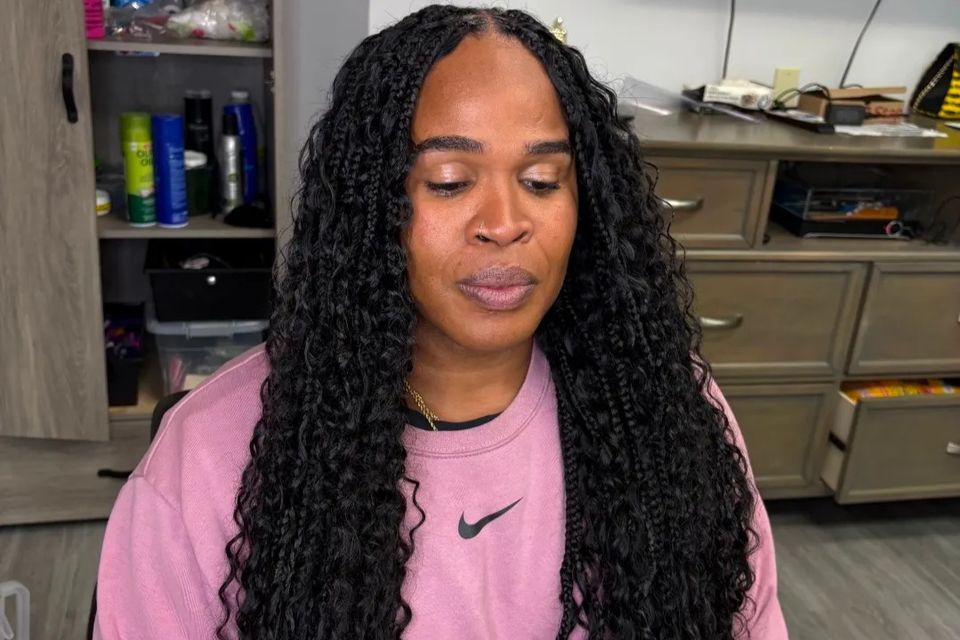 Client with long black goddess braids with wavy ends after hair braiding service in Los Angeles CA