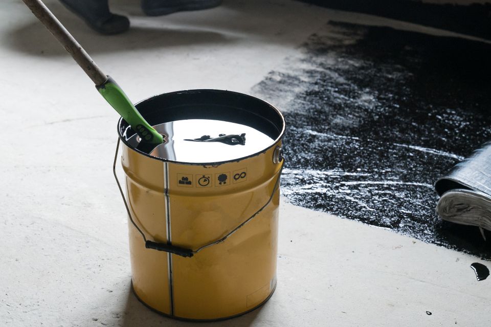 Medium applying hot resin to the floor for waterproofing roller and bucket of resin