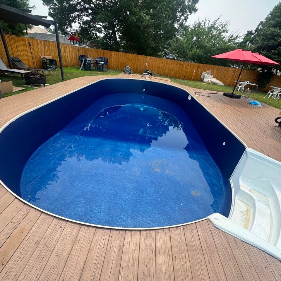 Oval above ground pool with dark blue liner and deck surround being filled