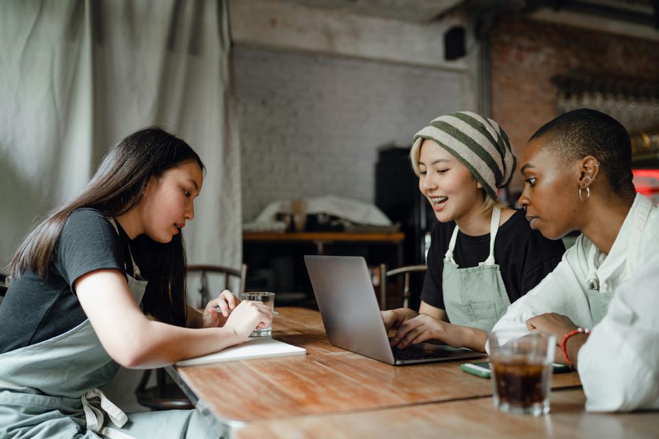 Three staff ladies sitting at a cafe discussing business results