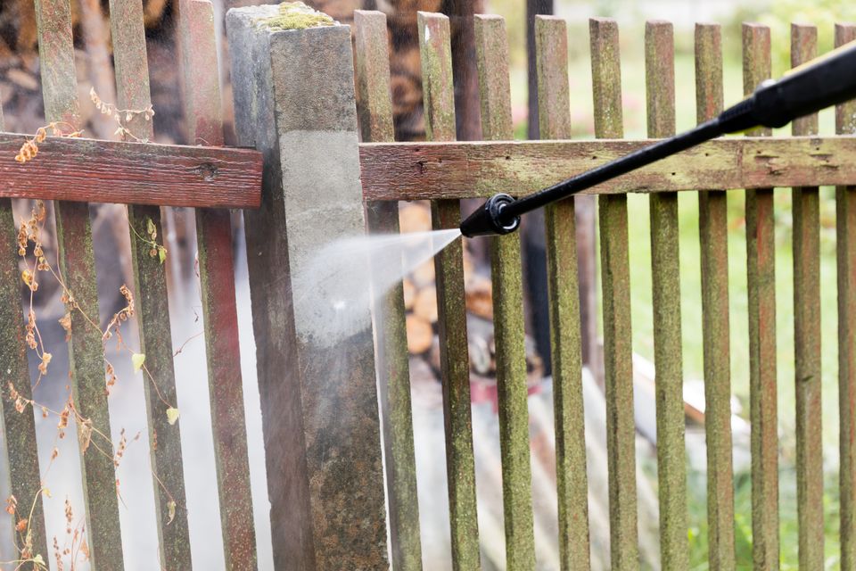 Cleaning dirty garden fence post with high pressure washer