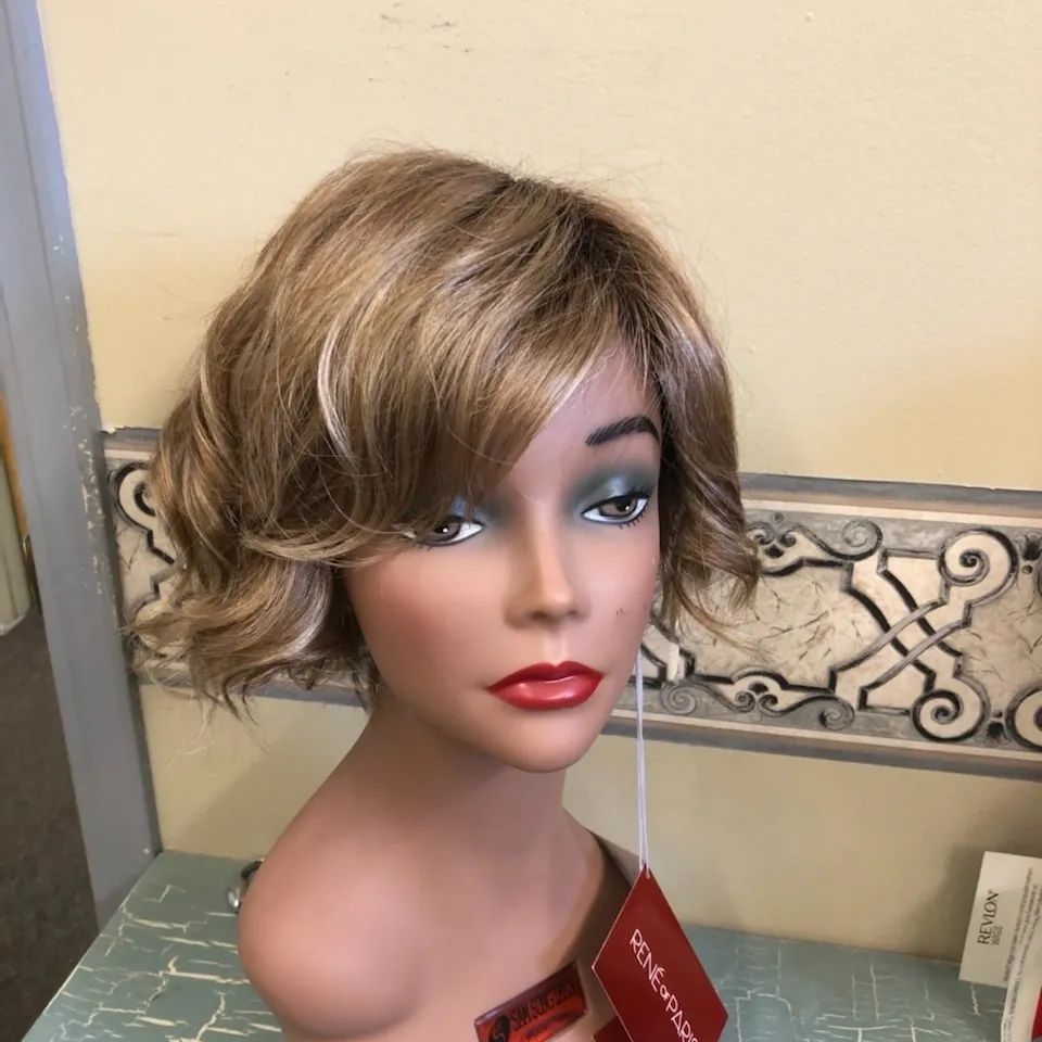 Short blonde layered wig with side-swept bangs and soft curls displayed on a mannequin at Shears Wigs & Hairpieces Salon.