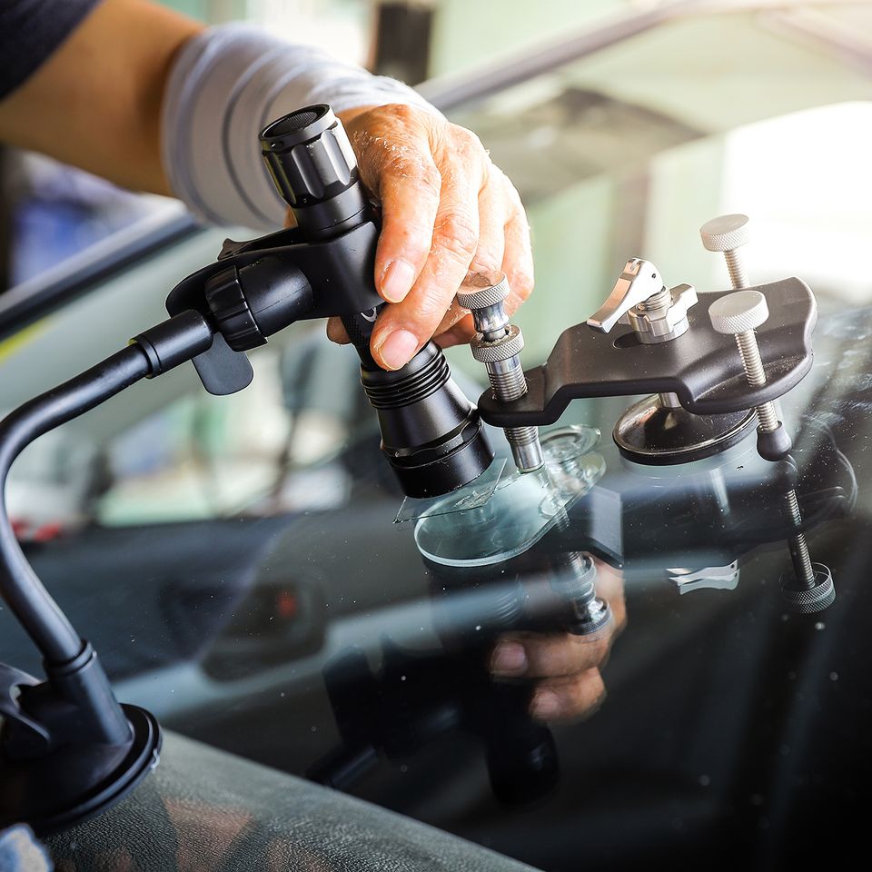 Technician repairing a windshield chip using professional auto glass repair equipment.