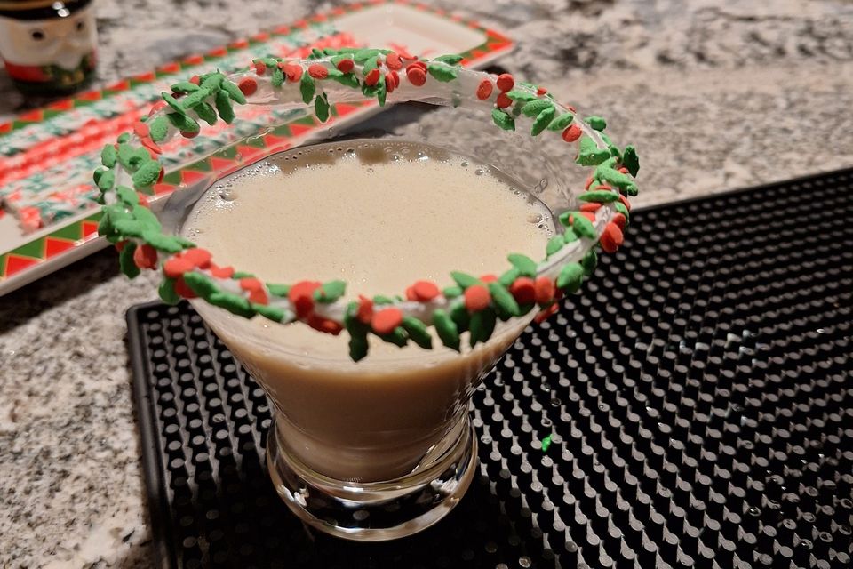 Sugar cookie martini with red and green sugar rim in a glass on a bar mat