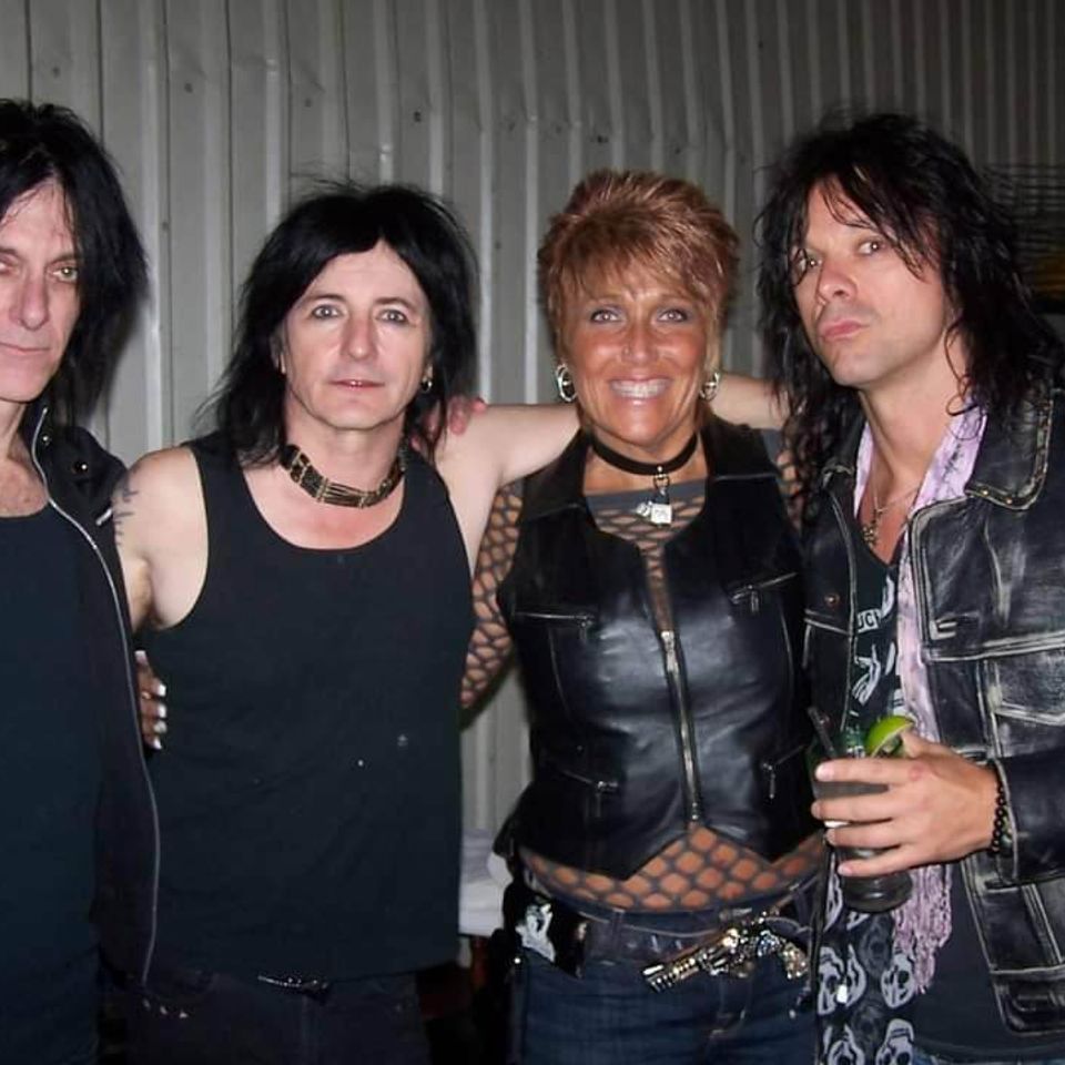 Kelly posing with three rock musicians backstage after a concert.