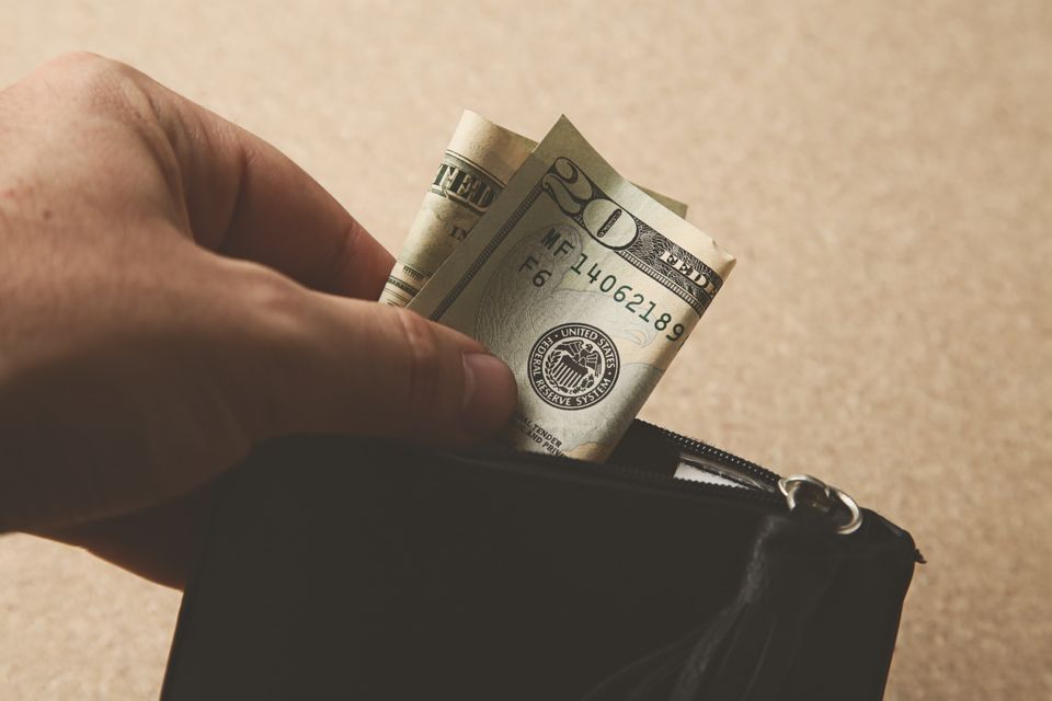 Closeup shot person putting some money his leather wallet