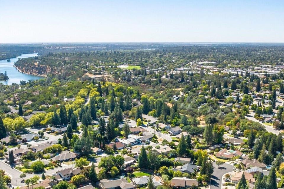 Aerial drone view of Orangevale, California, showcasing large residential lots, equestrian properties, and the dense native oak tree canopy near the American River Parkway.