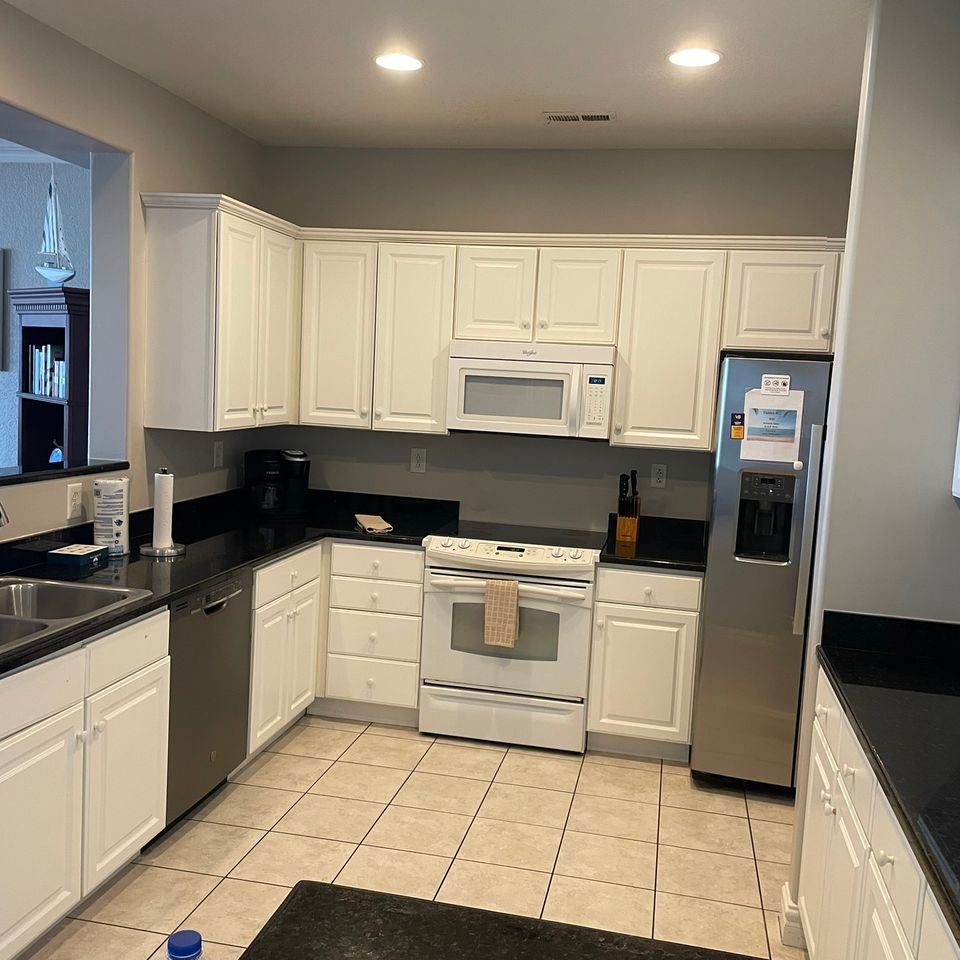 Clean kitchen with white cabinets and black counters after house cleaning service in Virginia Beach VA