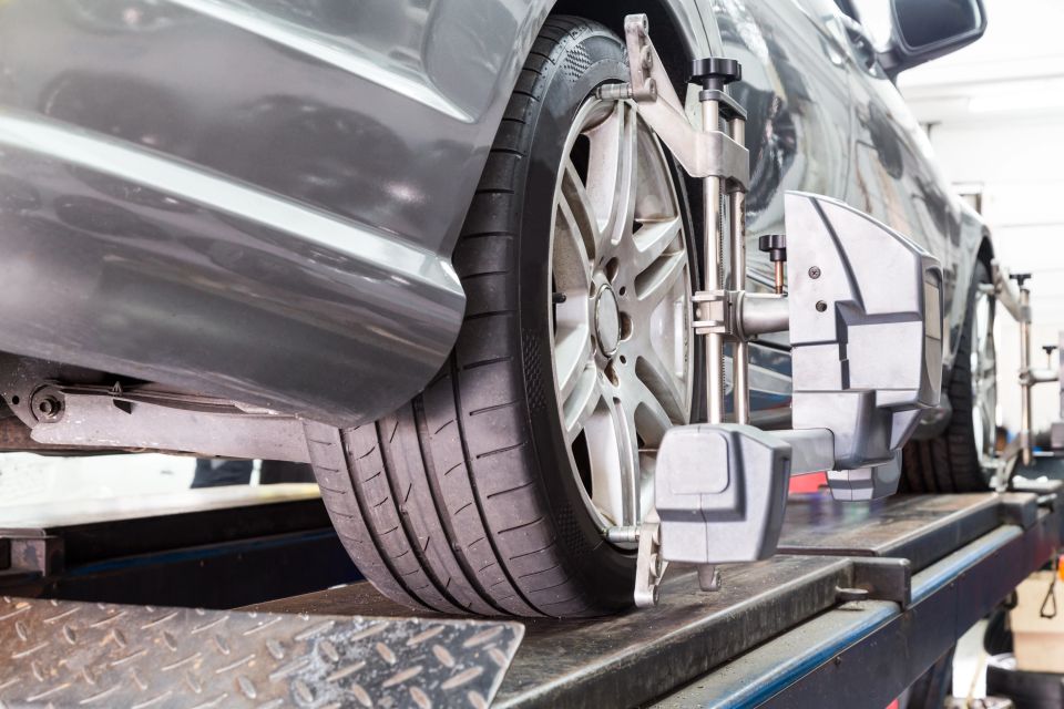 Closeup of tire clamped with aligner undergoing auto wheel alignment in garage