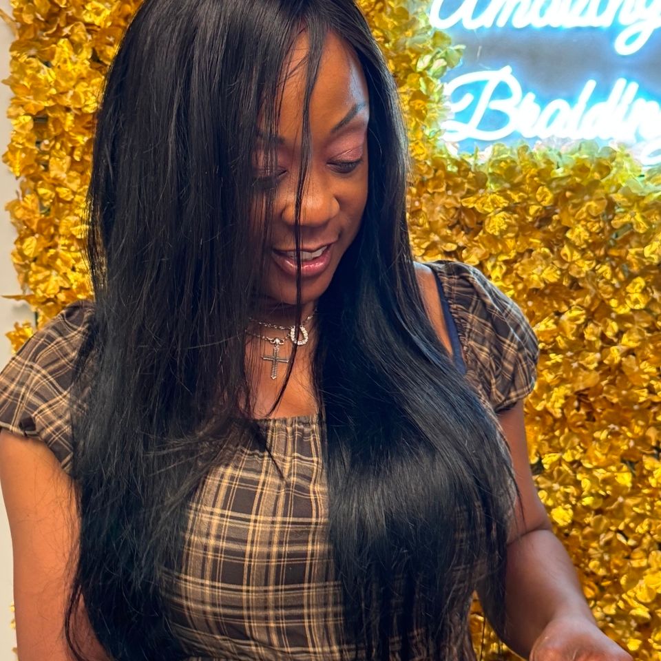 Client with long straight sew in hair extensions in front of the salon flower wall in Los Angeles CA