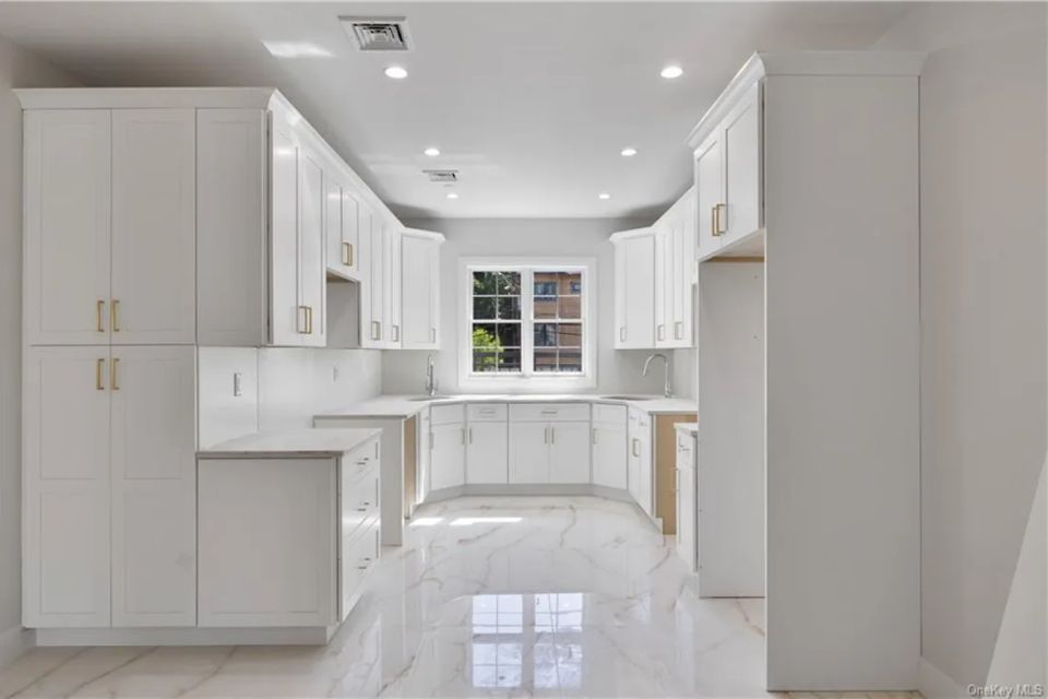 Compact white kitchen with custom cabinetry and modern finishes by Ultimate Kitchens.