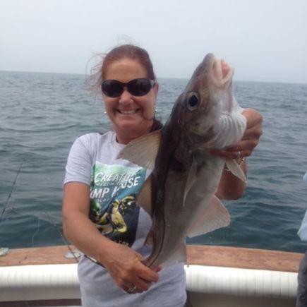 Woman on boat sunglasses holding caught haddock