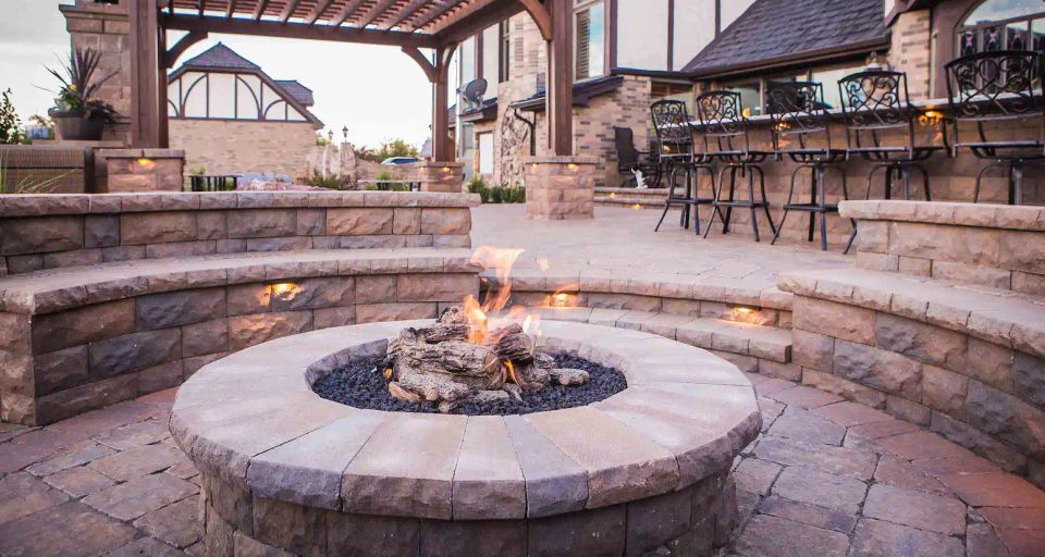 Custom stone fire pit with paver patio, seating walls, and outdoor living space at a luxury backyard project in Charlotte NC