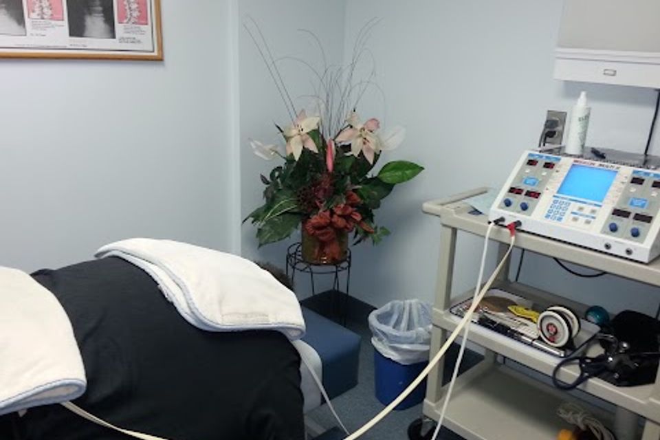Chiropractic treatment room with an adjustment table and therapy equipment prepared for patient care at Massaro Chiropractic LLC.