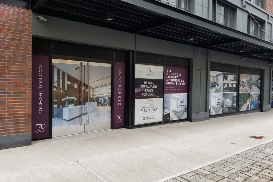Deep red and white printed vinyl panels on storefront windows and columns beneath a building canopy