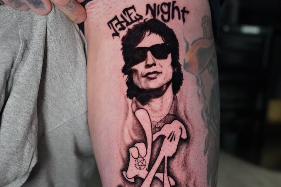 Image of a man's tattoo of the Night Stalker in black and grey and whhit and a blue mouse under the night stalker tattoo, very detailed and lots of definition