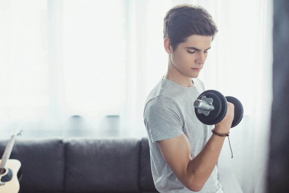 Teen curling a dumbbell at home during athletic training
