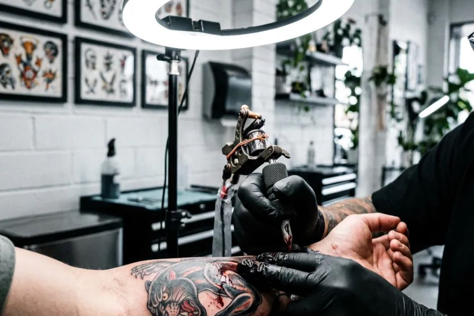  Local tattoo artist working on traditional panther design with sanitary equipment