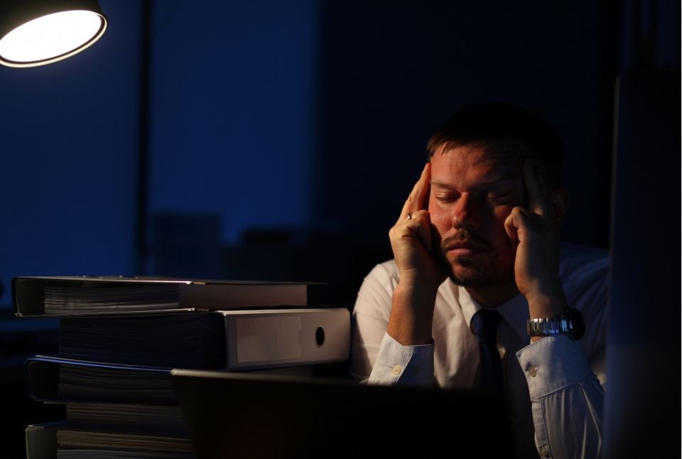 Person sitting tired at laptop, dim lighting