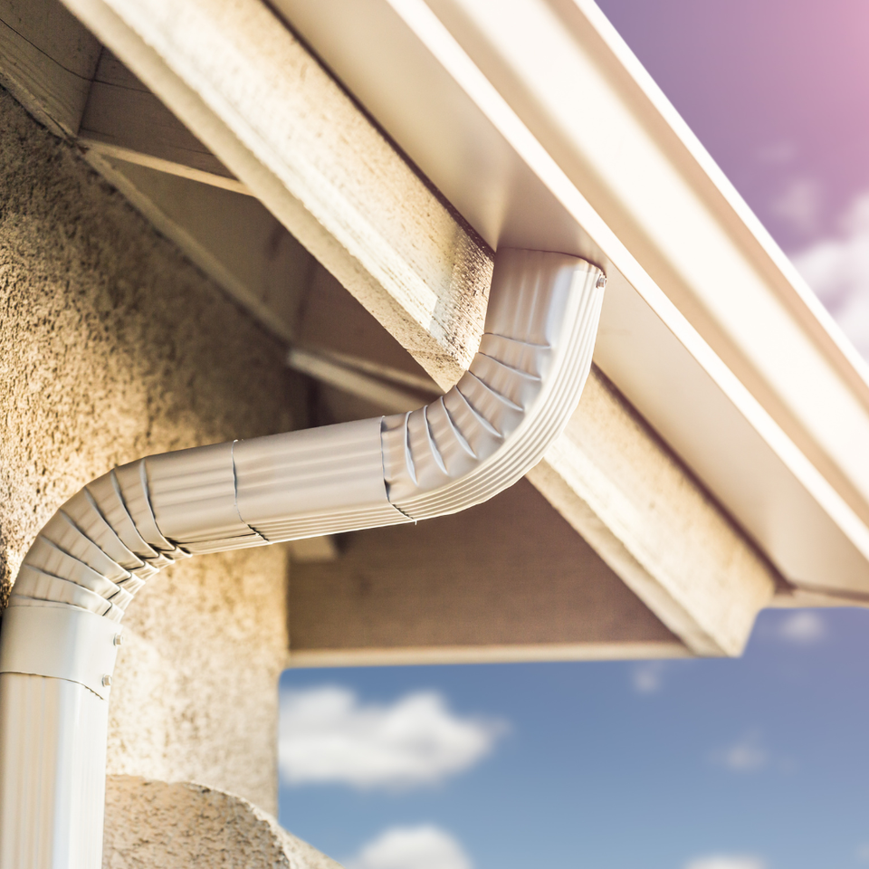 White seamless gutter and downspout system installed to improve drainage and protect the home's exterior.