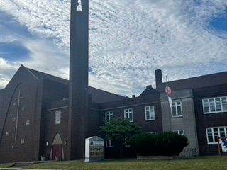 Exterior view of Grace Evangelistic Temple Church featuring its brick architecture, church tower, and welcoming grounds beneath a bright sky.