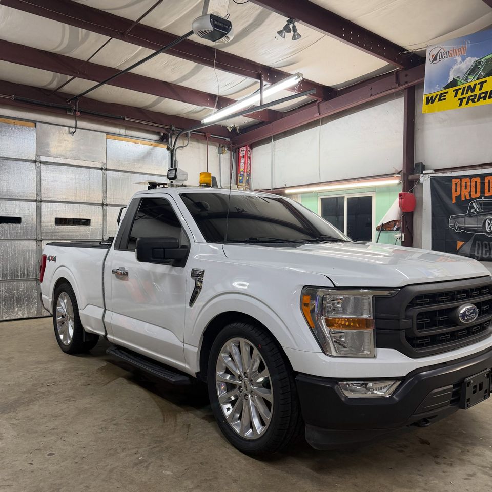 White Ford F-150 regular cab with tinted windows in a Moyock North Carolina tint shop bay