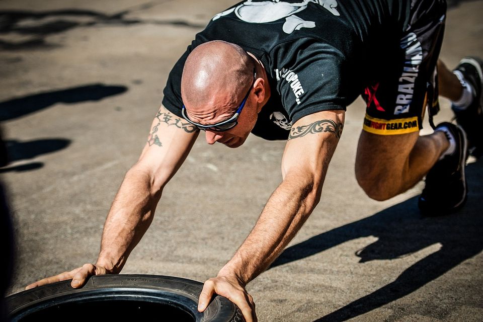 Exercising Picture of an athlete pushing a tire across the parking lot for leg, arm and core strength