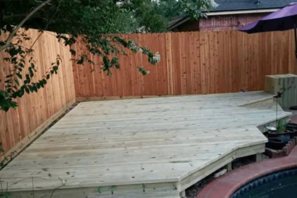 Completed wooden deck by pool and near new wooden fence