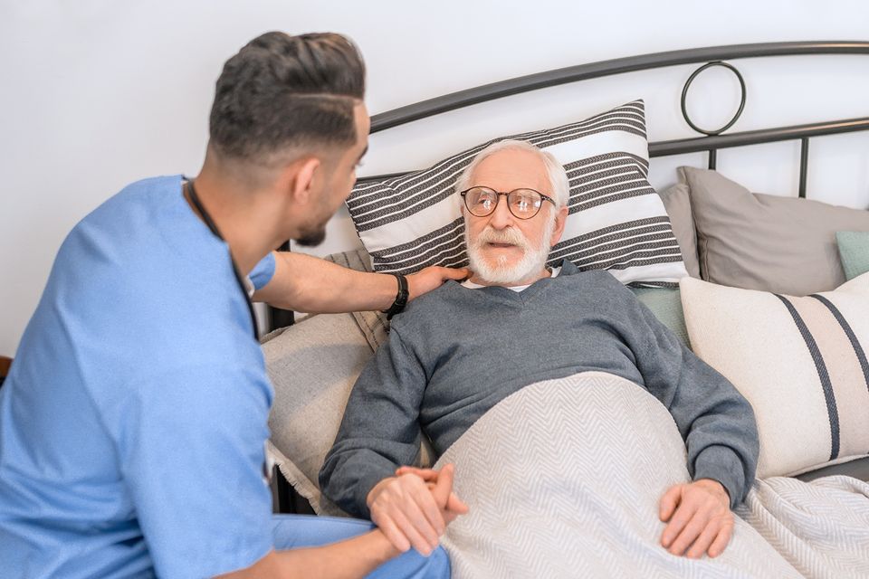 Family caregiver comforting elderly man at home through Medicaid support