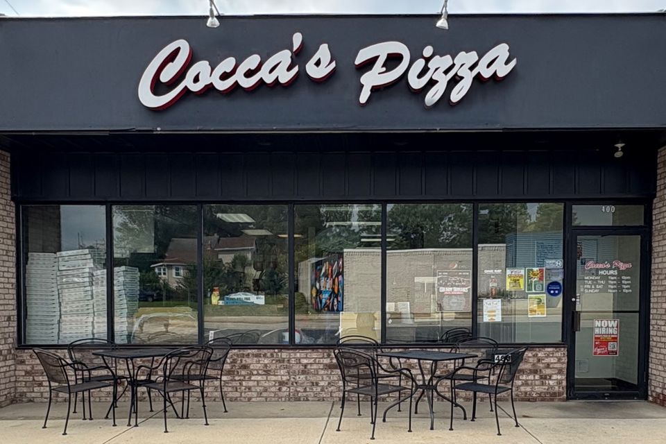 Cocca’s Pizza Girard, Ohio restaurant featuring a black façade, large front windows, outdoor patio seating, and a white Cocca’s Pizza sign above the entrance.